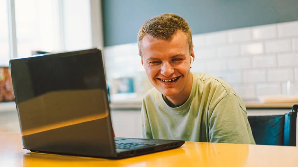 Young blind man using a computer and smiling