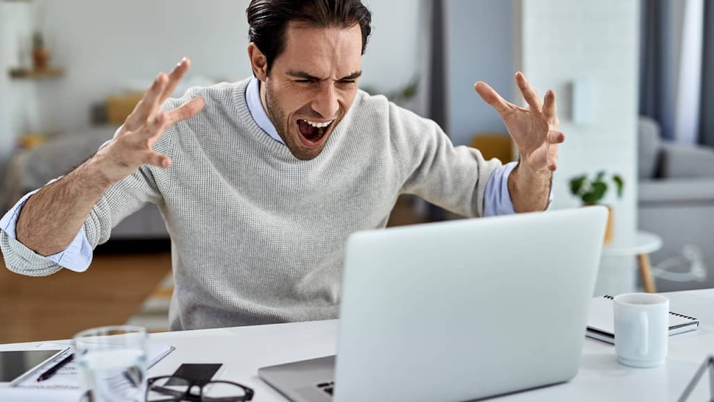 Frustrated businessman screaming while working on a computer at home