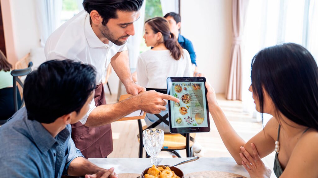 A group of people sitting at a table in a restaurant, with a tablet in their hands.