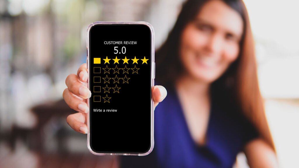 A woman holding up a smartphone displaying a five star rating for a restaurant website.