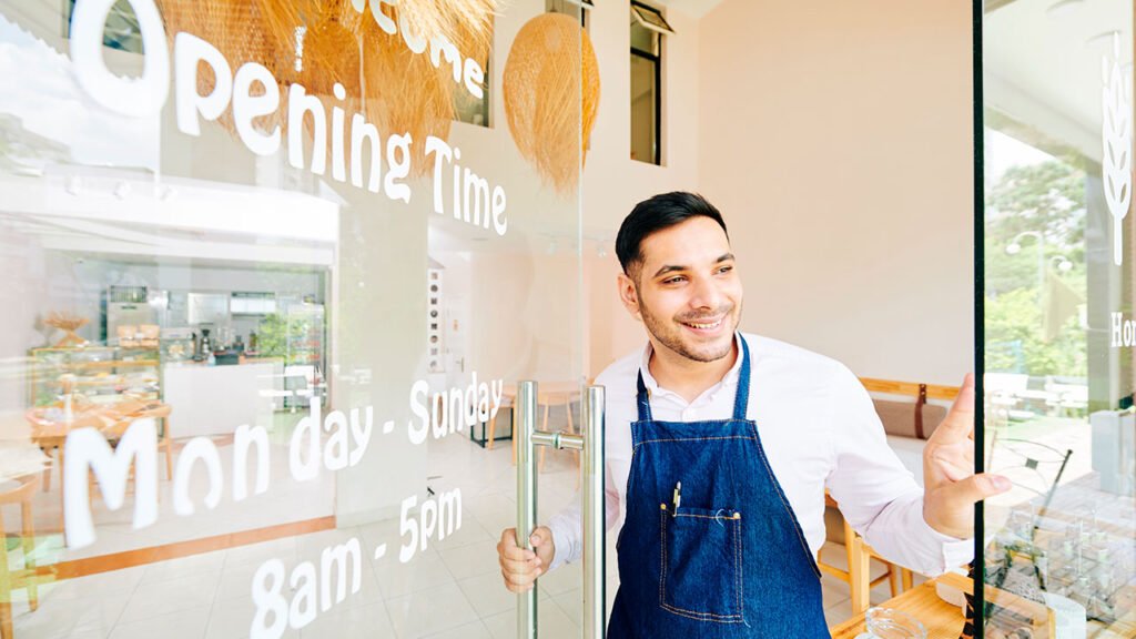 A man in an apron standing in front of a glass door, representing the ambiance of a restaurant website.